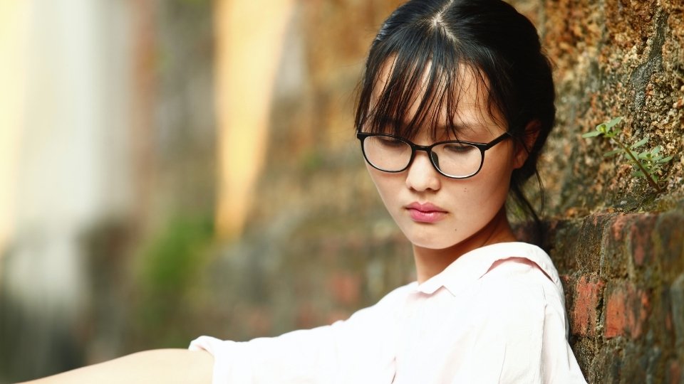 Why Is It Dangerous to Mix Prescription Drugs With Alcohol a woman looks down as she considers the consequences of stimulants and hear medicines.