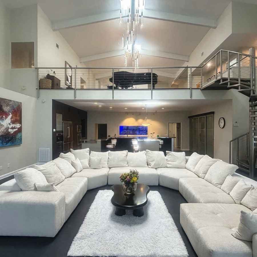 Living room with large sectional couch looking at the loft with a grand piano